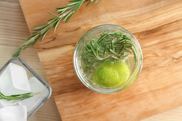 Jar with fresh rosemary drink on wooden board