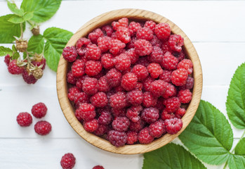 ripe red raspberries in a wooden bowl