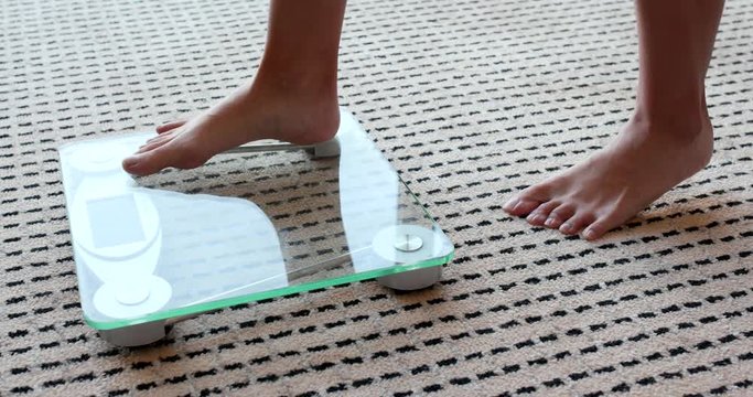 Female measuring weight on health scale