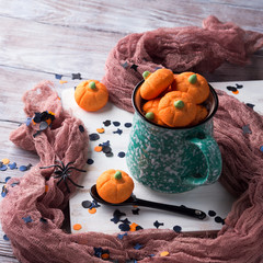 Mug of hot chocolate with Pumpkin shaped halloween marshmallows with holiday decorations. Children party