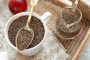 Fototapeta na wymiar Chia seeds in cup and spoon on wicker tray
