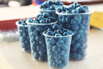 Fresh blueberries in plastic cups at market, closeup