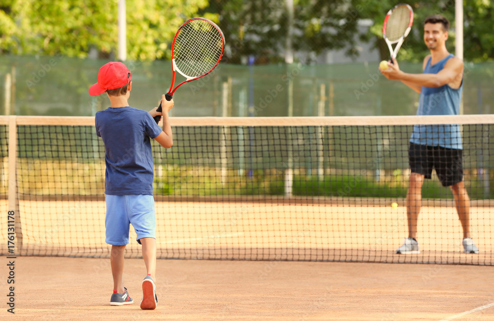 Poster Young trainer with little boy playing tennis on court