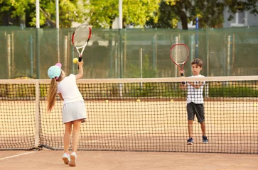 Badkamer foto achterwand Cute little children playing tennis on court © Africa Studio