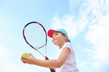 Deurstickers Cute little girl with tennis racket and ball against sky © Africa Studio