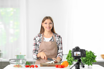 Young female blogger recording video in kitchen