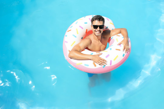 Young man with inflatable donut in swimming pool