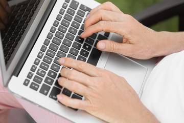 Mature woman working with laptop outdoors, closeup