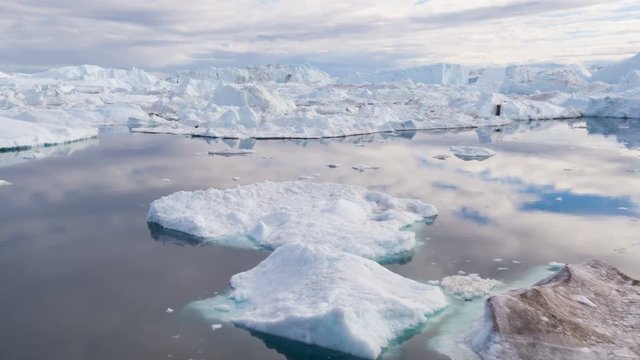 Iceberg and ice from glacier in arctic nature landscape on Greenland. Aerial video drone footage of icebergs in Ilulissat icefjord. Affected by climate change and global warming.