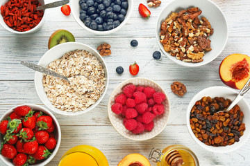 Composition with nutritious oatmeal and different ingredients for breakfast on wooden background