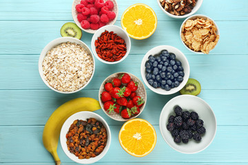 Composition with nutritious oatmeal and different ingredients for breakfast on wooden background