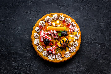 Pumpkin pie for halloween decorated gummy spiders. Black background top view copyspace
