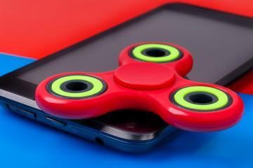 Close-up shot of fidget spinner lying on smartphone. Two-tone background