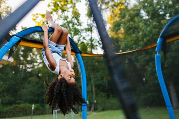 A young girl hanging upside down on a trampoline