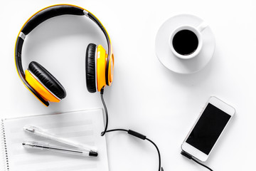 Worktable of composer today. Headphones, phone, music notes on white background top view