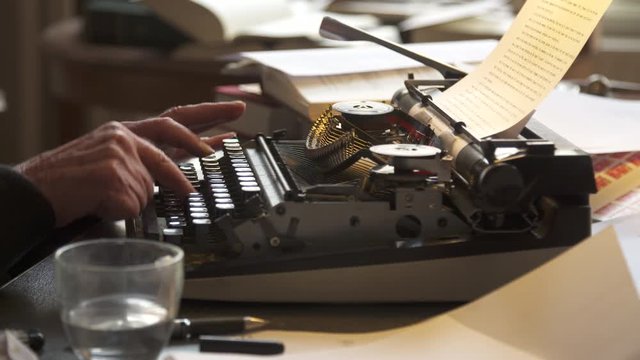 Typing on a piece of paper on a typewriter, medium side shot.