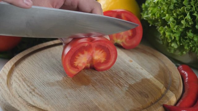 Man's hands cutting the tomato into pieces
