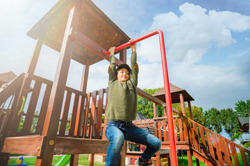 curious fearless little girl climbing on playground alone in sunny weather