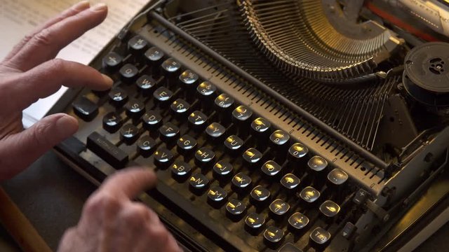 Old male hands typing on typewriter, top shot.