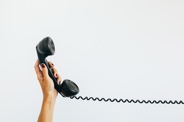 woman's hand holding a vintage telephone  with cord stretched out