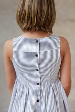 Girl wearing a striped dress with button details on the back