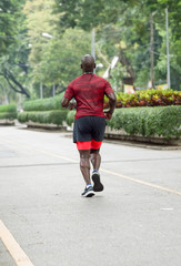 black man running in park from back view