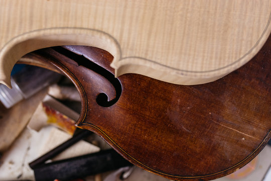 Unfinished and finished violin bodies on a workbench - Powered by Adobe