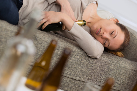 alcoholic woman sleeping holding the bottles