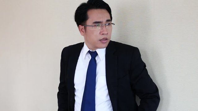 worry asian businessman with glasses and suit is waiting for someone with stressful and worry