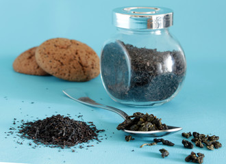dried black tea in the jar with the spoon on the blue table