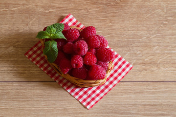 Fresh ripe raspberries in a small basket - 176141134