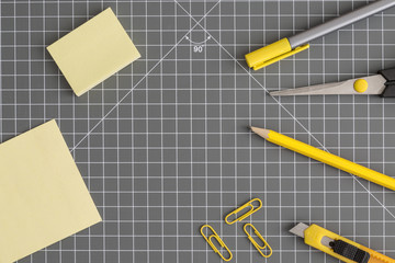 Yellow office utensils on a grey crafting mat
