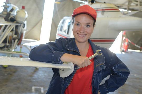 young female with wrench fixing part of jetliner