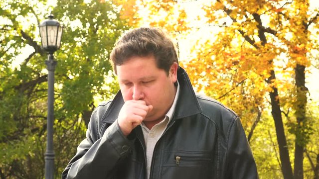 Portrait man coughs in autumn Park