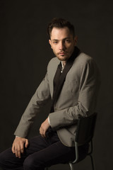 young serious man with an unshaven face in a suit with a pensive face on a dark background