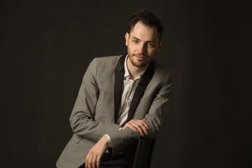 Fototapeta premium portrait of a young man with an unshaven face in a suit with a smile on a dark background
