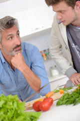 Father and son looking at eachother over vegetables