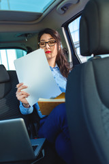 Beautiful young business woman sitting in the car looking at her planner.