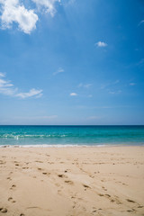 Fototapeta na wymiar Beautiful tropical sandy beach over blue sea and sky background