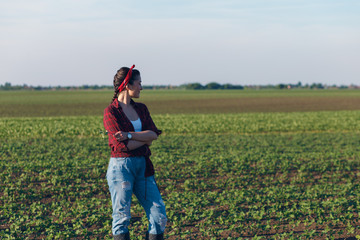 Female farmer standing in a soybean field and examining crop. She is holding young plant in her arms.