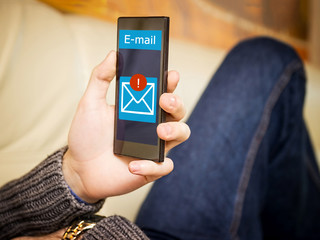 A young man with a mobile while lying on the couch.