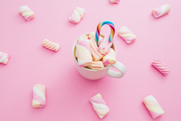Colored marshmallow with cappuccino mug and cane sugar on blue background. Flat lay, top view