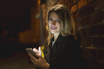 young handsom caucasian woman holding a smartphone on the dark city