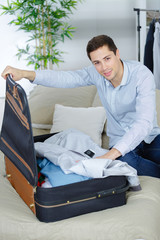 Obraz premium close up of businessman packing clothes into travel bag
