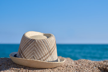 Men’s sunhat on the beach sand against sea. Back view.