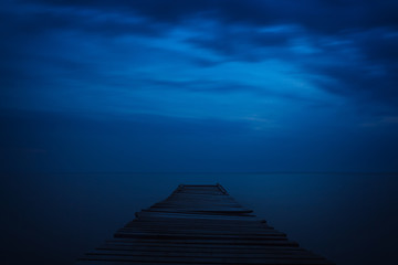 Wooden sea pier night. Dark sky with clouds.