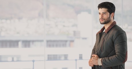 Man in coat by window of bright city