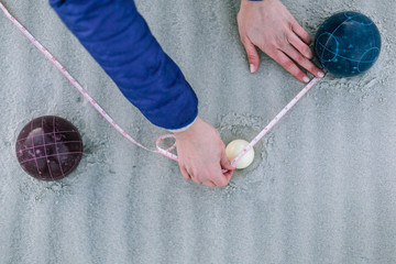 Measuring distance to determine winner of bocce game on beach