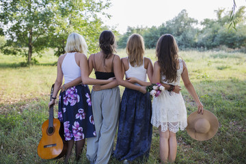 Back view of four happy female friends in nature