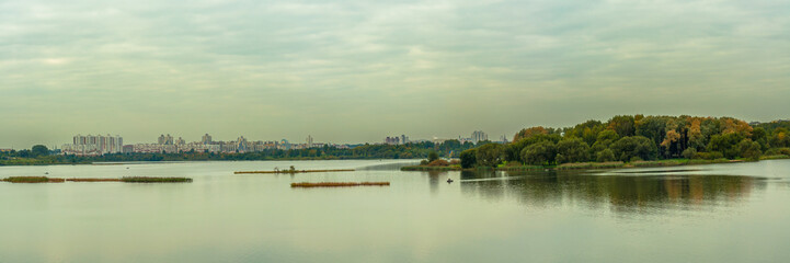 panoramic view of a large urban reservoir with an island and a modern residential area on the opposite coast